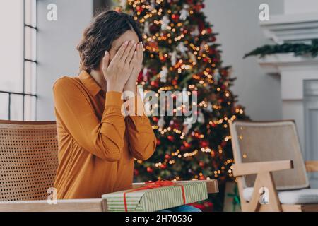 Neugierige Frau, die die Augen mit den Händen bedeckt und was in der Weihnachts-Geschenkbox erraten hat Stockfoto