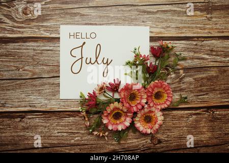 Hallo Juli Typografie Text mit Blumen auf Holzhintergrund Stockfoto