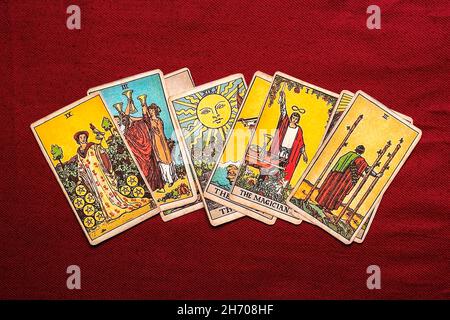 Legt Tarot-Karten, Kerze, Kristall auf rotem Hintergrund Flat Lay Draufsicht Wahrsagerei, Vorhersage, Eoterik, Tarot-Karten-Konzept. Stockfoto