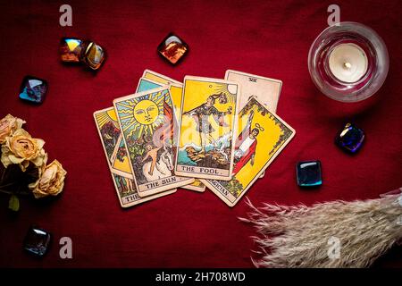 Legt Tarot-Karten, Kerze, Kristall auf rotem Hintergrund Flat Lay Draufsicht Wahrsagerei, Vorhersage, Eoterik, Tarot-Karten-Konzept. Stockfoto