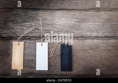 Drei verschiedene Pappanhänger auf dem dunklen Holzhintergrund Stockfoto