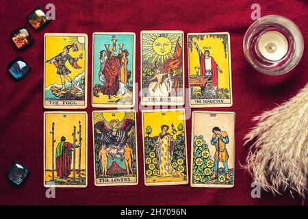 Legt Tarot-Karten, Kerze, Kristall auf rotem Hintergrund Flat Lay Draufsicht Wahrsagerei, Vorhersage, Eoterik, Tarot-Karten-Konzept. Stockfoto