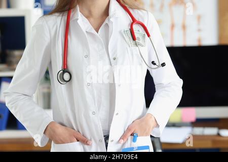 Chefarzt in der Klinik mit einem Haufen Geld in der Tasche mit medizinischem Kleid Stockfoto