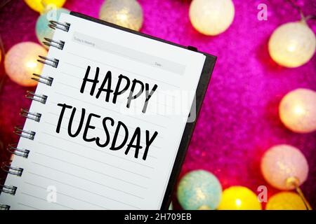 Happy Tuesday Text Notizblock Mockup und LED-Baumwollkugeln Dekoration auf rosa Bokeh Hintergrund Stockfoto