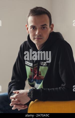Porträt eines jungen Mannes in schwarzem Hoodie, der auf die Kamera schaut. Stockfoto