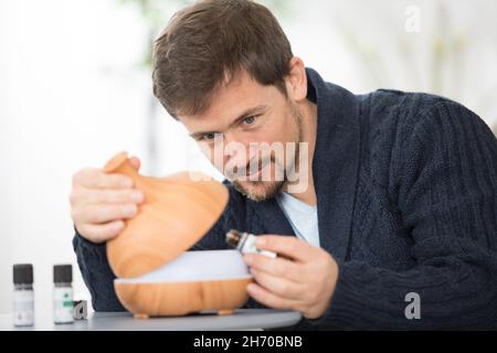Hübscher Mann, der ätherisches Öl in den Diffusor gießt Stockfoto