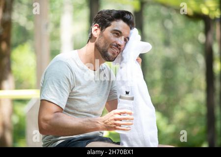 Junger Mann, der sich nach dem Joggen auf der Parkbank ausruhte Stockfoto