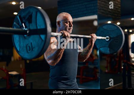 Älterer Bodybuilder-Athlet trainiert im Fitnessstudio und pumpt dabei Bizepssmuskeln auf. Sportlicher Typ mit Langhantel Stockfoto