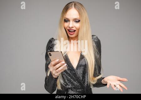 Eine hübsche Dame mit offenen Augen, die ihr Mobiltelefon hält Stockfoto