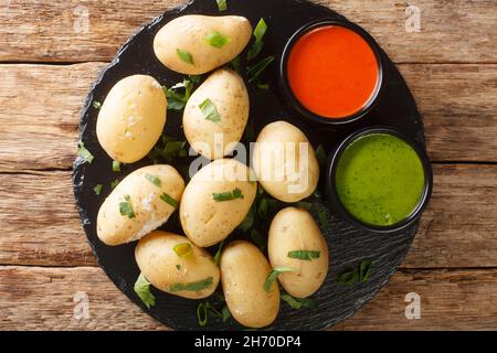 Kanarische Faltenkartoffeln Papas arrugadas mit einer Mojo rojo- und Mojo verde-Saucen schließen sich auf dem Teller auf dem Tisch an. Horizontale Draufsicht von oben Stockfoto