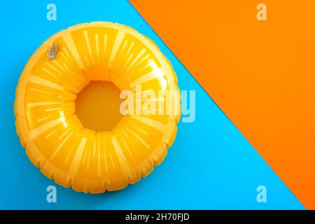 Sommerurlaub und Sicherheitsausrüstung zum Schwimmen mit einer Rettungsboje isoliert auf einem orangefarbenen und blauen minimalistischen Hintergrund mit Kopierraum Stockfoto