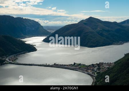 Lugano, Schweiz - Oktober 6th 2021: Blick vom Monte San Salvatore auf den Damm zwischen Melide und Bissone, der den See in zwei Teile trennt. Stockfoto