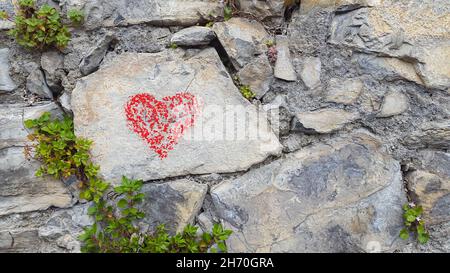 Lugano, Schweiz - April 19th 2015 - Ein rotes Herz auf einer Steinmauer mit Vegetation gemalt Stockfoto