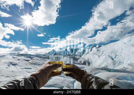 Zwei Hände mit Gläsern und Getränken mit Eiswürfeln aus dem Perito Moreno-Gletscher Stockfoto