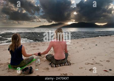 Ein junges Paar sitzt mit Händen auf der Cairns Esplanade in Queensland, Australien, während sie die letzten Momente der totalen Sonnenfinsternis beobachten. Stockfoto