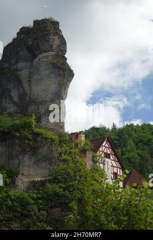 Berühmte Felsen mit Aussichtspunkt Fahnenstein über traditionellen deutschen Fachhäusern, Tüchersfeld, Pottenstein, Oberfranken, Bayern, Deutschland Stockfoto