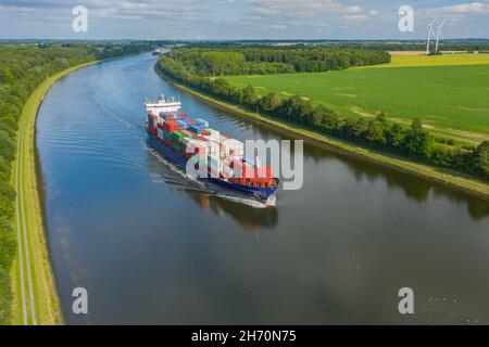 Containerschiffe auf dem Nord-Ostsee-Kanal und Windmühle im Hintergrund. Stockfoto
