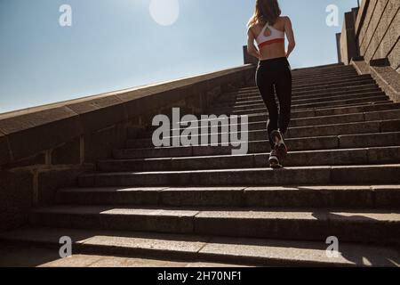 Junge Sportlerin trainiert an sonnigen Sommertagen Steintreppen hoch Stockfoto