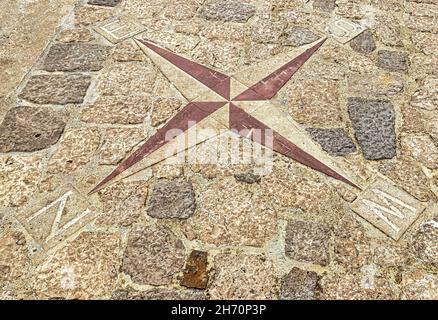 Ein Navigationskompass, der auf dem Bürgersteig angelegt ist. Pfeile zeigen nach Norden, Süden, Westen und Osten. Stockfoto