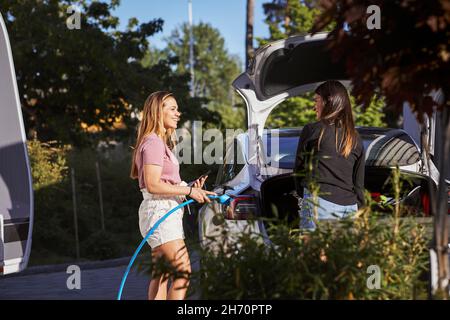 Frau lädt Elektroauto Stockfoto