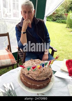 Mann mit Schokolade Geburtstagskuchen im Garten Gaceebo Stockfoto