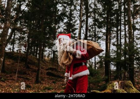 Mann mit Weihnachtsmann-Kostüm, der einen Sack trägt Stockfoto