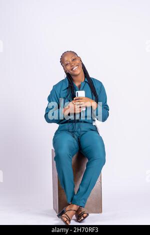 Vertikale Aufnahme einer glücklichen jungen afrikanischen Frau mit einem Smartphone auf weißem Hintergrund isoliert. Stockfoto
