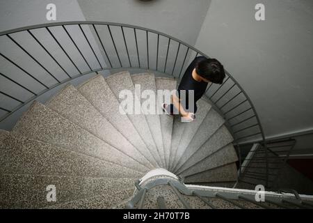 Junge Frau, die eine Wendeltreppe hinuntergeht Stockfoto