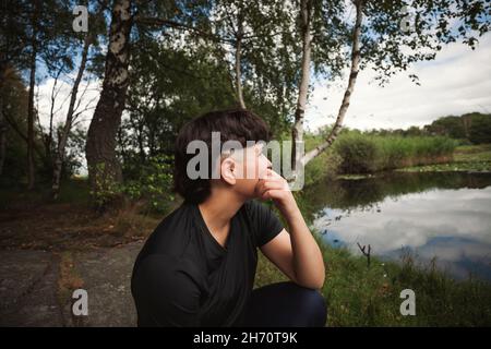 Junge Frau, die sich am Seeufer entspannt Stockfoto