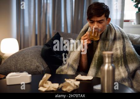 Kranker junger Mann, der Tee trinkt Stockfoto