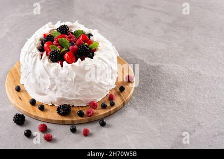 Köstlicher Pavlova-Kuchen mit Baiser und frischen Beeren auf grauem Stein Stockfoto