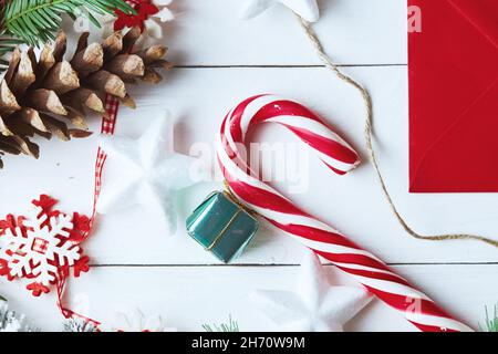 Schöne Weihnachtskomposition auf weißem Hintergrund mit Weihnachtsgeschenkschachteln, verschneiten Tannenzweigen, Nadelholzzapfen, Weihnachtsdekoration, Karamellstab und Stockfoto