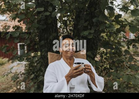 Lächelnder Mann, der im Garten Kaffee getrunken hat Stockfoto