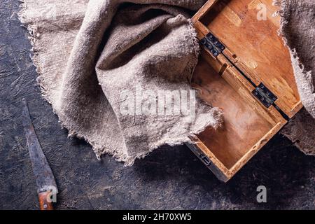 Vintage Metzgermesser und alte Holzkiste auf Steinküchenoberfläche. Draufsicht mit selektivem Fokus Stockfoto