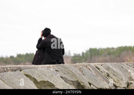 Mann, der auf steinerner Groyne sitzt Stockfoto