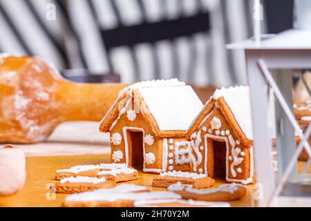 Weihnachts-Lebkuchenhäuser und verschieden geformte Kekse mit Zuckereier auf Holztisch, Nahaufnahme mit selektivem Fokus Stockfoto