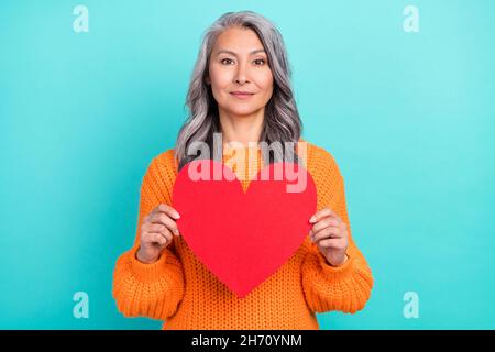 Porträt einer attraktiven friedlichen grauhaarigen Frau mit Herzform Zuneigung isoliert über hellen türkisfarbenen Hintergrund Stockfoto