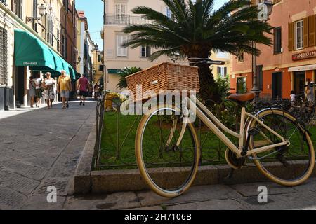 Ein altmodisches Fahrrad, das im Sommer in der engen Hauptallee (dem 'Budello') von Alassio, Savona, Ligurien, Italien, geparkt ist Stockfoto