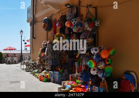 Ein Touristengeschäft, das Strandspielzeug und Souvenirs an der Uferpromenade von Alassio an einem sonnigen Sommertag verkauft, Savona, Ligurien, Italien Stockfoto