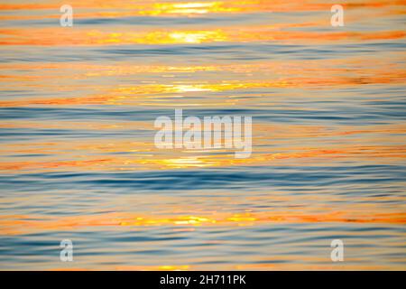 Sonnenstrahlen werden bei Sonnenaufgang auf der Wasseroberfläche reflektiert und bilden ein abstraktes Muster. Bodensee, Schweiz Stockfoto