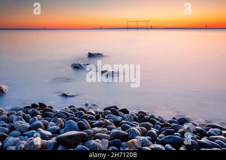 Blick von Arbon über den Bodensee bei Sonnenaufgang, mit Steinen im Vordergrund und mit langsamer Verschlusszeit fotografiert, Schweiz Stockfoto