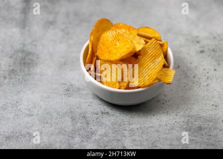 Kartoffelchips in der Schüssel. Im Ofen gebackene knusprige Kartoffelchips auf grauem Hintergrund mit Platz zum Kopieren. Schüssel lecker Stockfoto