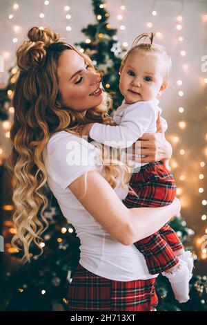 Attractive young mum hold a baby on her knees in christmas atmosphere Stockfoto