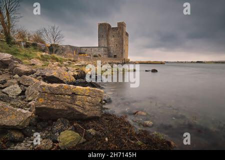 Dramatische, wolkige Landschaft von Oranmore Castle an der felsigen Küste des Wild atlantic Way in der Grafschaft Galway, Irland Stockfoto