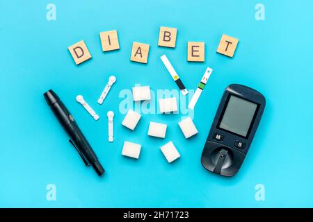 Glucometer, Zuckerwürfel auf blauem Hintergrund hohes Blutzucker- und Diabetes-Konzept Draufsicht Flat Lay 14. November - Weltdiabetestag. Stockfoto