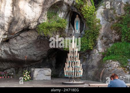 Lourdes, Frankreich - 28. August 2021: Frau, die vor der Höhle der Erscheinungen der heiligen Maria in Lourdes betet Stockfoto