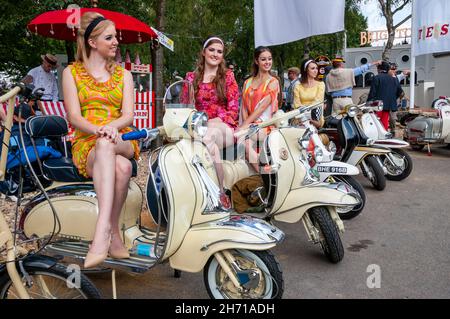 Frauen im Stil der 60er Jahre posieren auf alten Motorroller beim Goodwood Revival 2014. Lambretta Motorroller Stockfoto