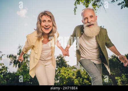 Portrait eines attraktiven fröhlichen Paares, das die Hände hält, um Urlaub zu verbringen und einen sonnigen Tag an der frischen Luft im Freien zu verbringen Stockfoto