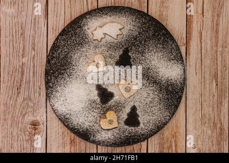 Weihnachtskekse in verschiedenen Formen in Zuckerglasur auf dunklem Teller mit Zucker bestreut, flach legen.Weihnachtskomposition mit traditionellen Linzer Christma Stockfoto