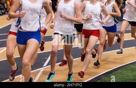 High School Mädchen laufen auf einer Indoor-Strecke während eines Leichtathletik-Wettbewerbs. Stockfoto